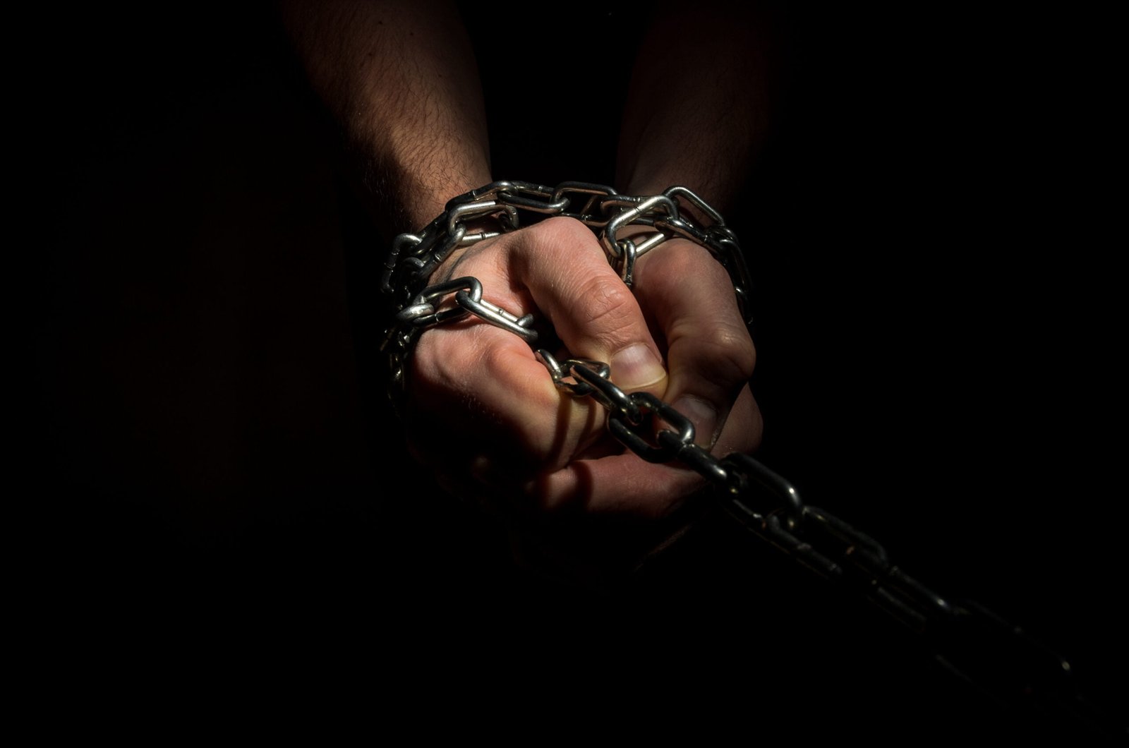 Hands-are-chained-in-chains-isolated-on-black-background-scaled-1